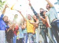 Happy friends enjoying party,throwing confetti and using smoke bombs colors at party outdoor - Young students having fun together Royalty Free Stock Photo