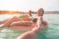 Happy friends floating with lilos mattress inside sea - Young real people having fun swimming in summer vacation - Youth lifestyle