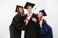 Happy friends graduates smiling holding diplomas looking at camera over white background. Royalty Free Stock Photo