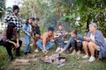 Happy friends group doing recreation with man playing guitar while friends and children grill marshmallow. Royalty Free Stock Photo