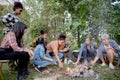 Happy friends group doing recreation with man playing guitar while friends and children grill marshmallow at camping together. Royalty Free Stock Photo