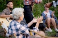 Happy friends group doing recreation with man playing guitar and friends and children singing at camping together. Royalty Free Stock Photo