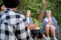 Happy friends group doing recreation with man playing guitar and friends and children singing at camping. Royalty Free Stock Photo