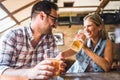 Happy friends having fun at bar - Young trendy couple drinking beer and laughing together Royalty Free Stock Photo