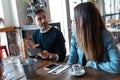 Happy friends group eating burgers while talking about work using digital tablet sitting in restaurant Royalty Free Stock Photo