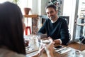 Happy friends group eating burgers while talking about work using digital tablet sitting in restaurant Royalty Free Stock Photo