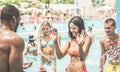 Happy friends having fun in aqua park on beach summer vacation - Diverse culture couples playing in swimming pool - Friendship, Royalty Free Stock Photo