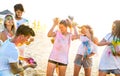 Happy friends having fun at beach party in holi colors summer festival - Young people millennial playing together