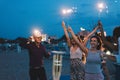 Happy friends having fun beach party outdoor with fireworks - Young people drinking champagne and dancing in summer vacation - Royalty Free Stock Photo