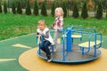 Happy friends having fun on carousel outdoors. Cute little girls enjoying at playground. Happy and healthy childhood. Modern
