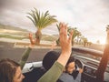 Happy friends having fun in convertible car on vacation - Young trendy people driving on cabriolet auto in summer road trip Royalty Free Stock Photo