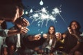 Happy friends having fun outdoors. Cheerful people enjoying party with sparklers in park Royalty Free Stock Photo