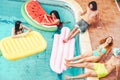 Happy friends having fun in swimming pool during summer tropical vacation - Young people relaxing and floating on air lilos Royalty Free Stock Photo