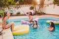 Happy friends having fun in swimming pool during summer vacation - Young people relaxing and floating on air lilo Royalty Free Stock Photo
