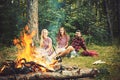 Happy friends having picnic in woods. Cheerful youngsters enjoying summer evening near campfire, weekend in countryside Royalty Free Stock Photo