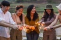 Happy friends holding fire sparkles. Group of young Travel join in fun at camping party in nature. Vacationers enjoy camping at Royalty Free Stock Photo