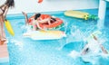 Happy friends jumping inside swimming pool  with tropical fruits lilos - Young people having fun diving into the water at beach Royalty Free Stock Photo