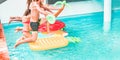 Happy friends jumping inside swimming pool with tropical lilos - Young people having fun diving into the water at beach resort Royalty Free Stock Photo