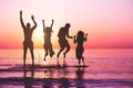 Happy friends jumping inside water on tropical beach at sunset - Group of young people having fun on summer vacation - Youth Royalty Free Stock Photo