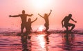 Happy friends jumping inside water on tropical beach at sunset - Group of young people having fun on summer vacation - Youth Royalty Free Stock Photo