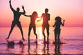 Happy friends jumping inside water on tropical beach at sunset - Group of young people having fun on summer vacation - Youth Royalty Free Stock Photo