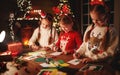 Happy friends kids draw decorations and write letter to Santa near Christmas tree