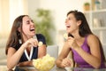 Happy friends laughing hilariously eating potato chips