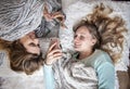 Happy friends laying on blankets with phones laughing Royalty Free Stock Photo