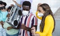 Happy friends listening music with vintage boombox and dancing while wearing face mask outdoor