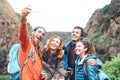 Happy friends making photo with mobile smartphone camera on mountain - Millennial young people trekking and having fun Royalty Free Stock Photo