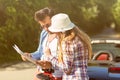 Happy friends with map driving in cabriolet car at country and pointing finger to something ahead Royalty Free Stock Photo