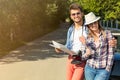 Happy friends with map driving in cabriolet car at country and pointing finger to something ahead Royalty Free Stock Photo