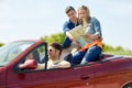 Happy friends with map driving in cabriolet car Royalty Free Stock Photo