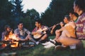 Happy friends playing music and enjoying bonfire Royalty Free Stock Photo