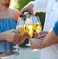 Happy friends pouring champagne sparkling wine into glasses outdoors at a beach Royalty Free Stock Photo
