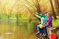 Happy friends sit fishing together near pond Royalty Free Stock Photo