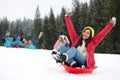 Happy friends sliding on sleds outdoors. Winter