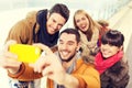 Happy friends with smartphone on skating rink Royalty Free Stock Photo