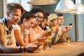 Happy friends with smartphones and drinks at bar Royalty Free Stock Photo