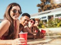 Happy friends, smile and relaxing in swimming pool for summer vacation, party or holiday break in the outdoors. Portrait Royalty Free Stock Photo