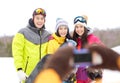 Happy friends with snowboards and smartphone