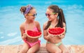 Cheerful girls eating watermelon near pool