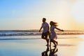 Family - father, mother, baby run on sunset beach Royalty Free Stock Photo