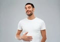 Happy full man touching tummy over gray background