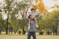 Happy Asian father giving son ride on his shoulders and holding  son hand like flying in the park Royalty Free Stock Photo