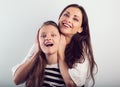 Happy fun laughing beautiful mother hugging her smiling daughter with love and closed her ears the hands on studio background Royalty Free Stock Photo