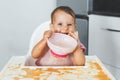 happy fun cheerful messy baby 9 months old sits in a highchair and eats lure vegetable puree soup, the concept of baby food