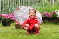 Happy fun pretty little girl in red raincoat with umbrella walking in park summer