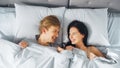 Happy and Fun Young Couple Lying under Blanket on a Bed, Looking at Each other and Smiling. Lovely Royalty Free Stock Photo