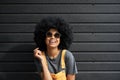 Happy funny African hipster woman wear stylish sunglasses against black wall.